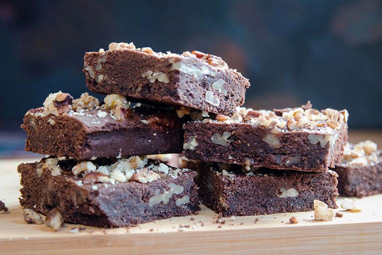 Una pila de brownies de chocolate y nuez, rociados con migas de nuez y nuez triturada, recién sacados del horno